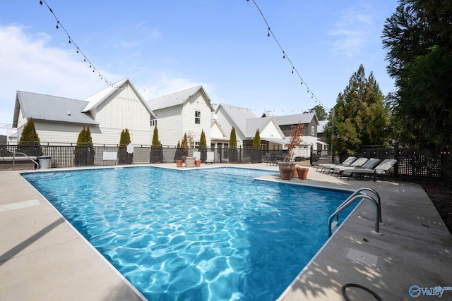 community pool featuring a patio, fence, and a residential view