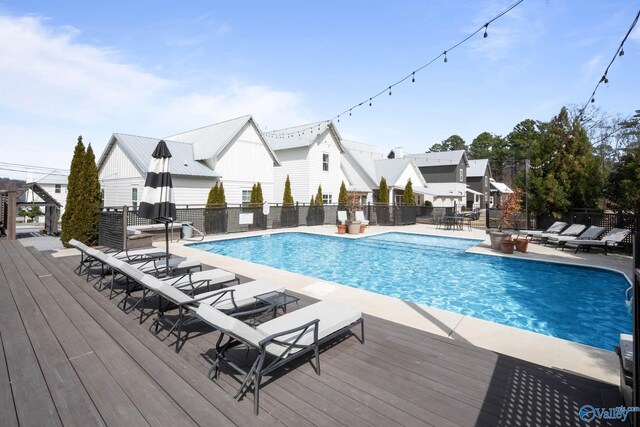 pool featuring a deck, fence, a fire pit, and a patio