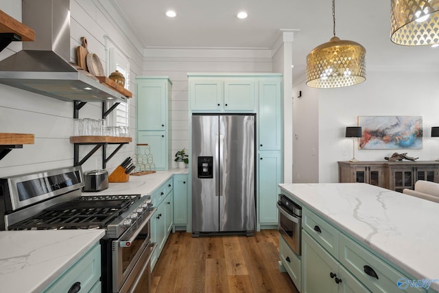 kitchen featuring green cabinets, stainless steel appliances, wall chimney exhaust hood, and crown molding