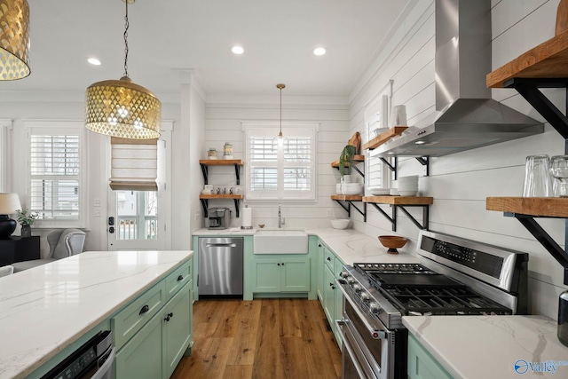 kitchen featuring open shelves, wall chimney range hood, stainless steel appliances, and green cabinets