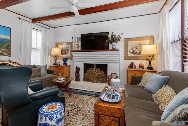 living room with ceiling fan, a fireplace, and beamed ceiling