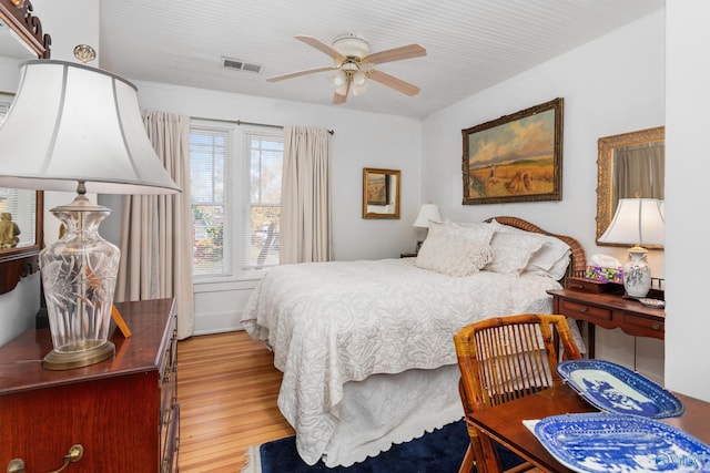 bedroom featuring ceiling fan, ornamental molding, and light hardwood / wood-style flooring