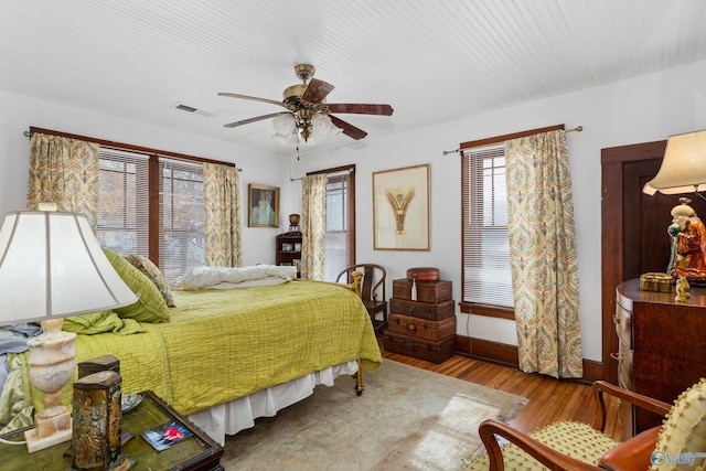 bedroom with multiple windows, ceiling fan, and hardwood / wood-style floors