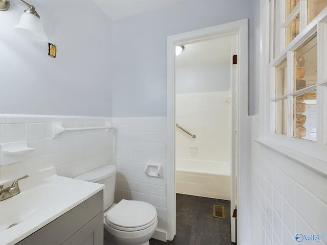 bathroom featuring vanity, toilet, a bathing tub, and tile walls