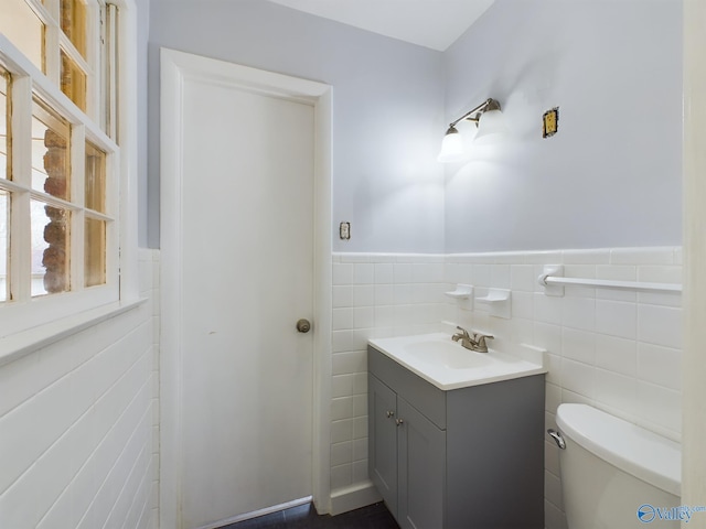 bathroom with vanity, tile walls, and toilet