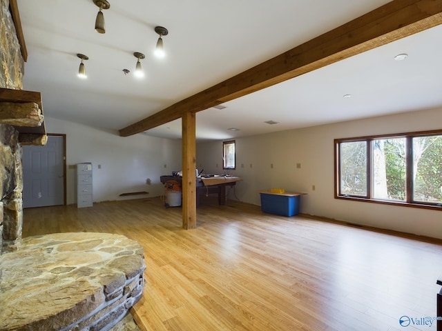 interior space with multiple windows, light wood-type flooring, and beam ceiling