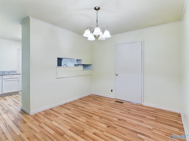 empty room with a notable chandelier, ornamental molding, and light hardwood / wood-style floors