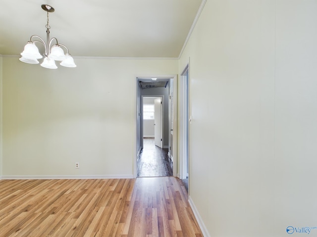 unfurnished room featuring hardwood / wood-style flooring, ornamental molding, and an inviting chandelier