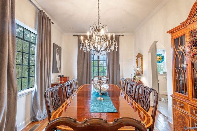 dining room with hardwood / wood-style floors, plenty of natural light, a notable chandelier, and ornamental molding