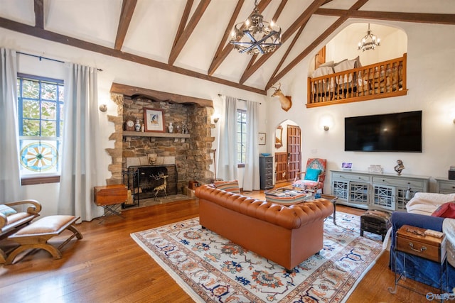 living room with a stone fireplace, high vaulted ceiling, hardwood / wood-style floors, and plenty of natural light