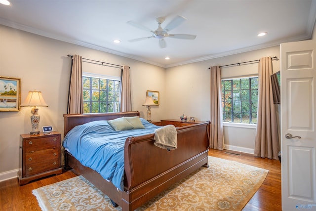 bedroom with dark wood-type flooring, ceiling fan, multiple windows, and ornamental molding