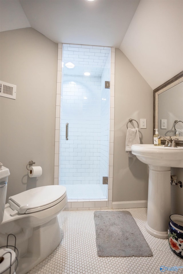 bathroom featuring toilet, lofted ceiling, tile patterned floors, and a shower with shower door