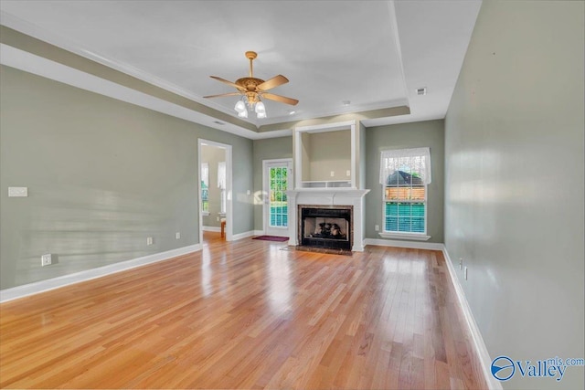 147 Singletree Dr, Hazel Green, AL 35750 - unfurnished living room featuring a tray ceiling, baseboards, a ceiling fan, and light wood-style floors