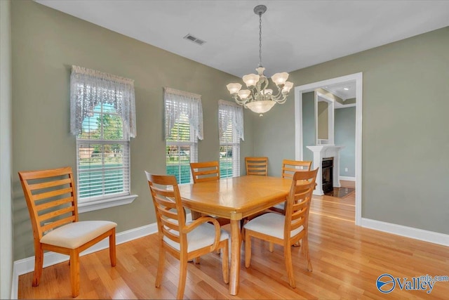 147 Singletree Dr, Hazel Green, AL 35750 - dining space with a notable chandelier, light wood-type flooring, baseboards, a fireplace with flush hearth, and visible vents