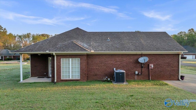 147 Singletree Dr, Hazel Green, AL 35750 - exterior space with central AC, a shingled roof, brick siding, and a lawn