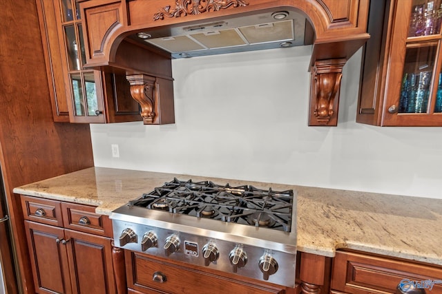 kitchen with light stone countertops, stainless steel gas cooktop, and exhaust hood