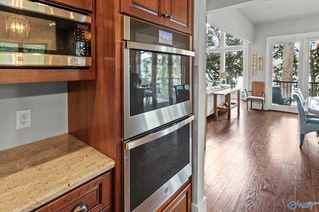 kitchen featuring light stone counters, stainless steel appliances, and wood-type flooring