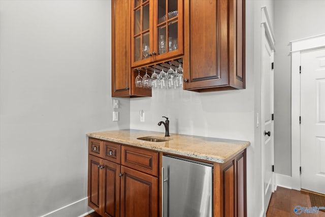 kitchen featuring stainless steel refrigerator, dark wood-type flooring, light stone countertops, and sink