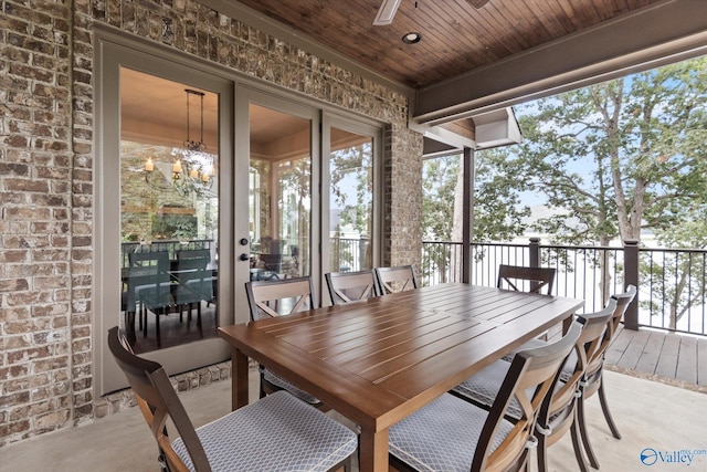 sunroom featuring ceiling fan with notable chandelier and wooden ceiling