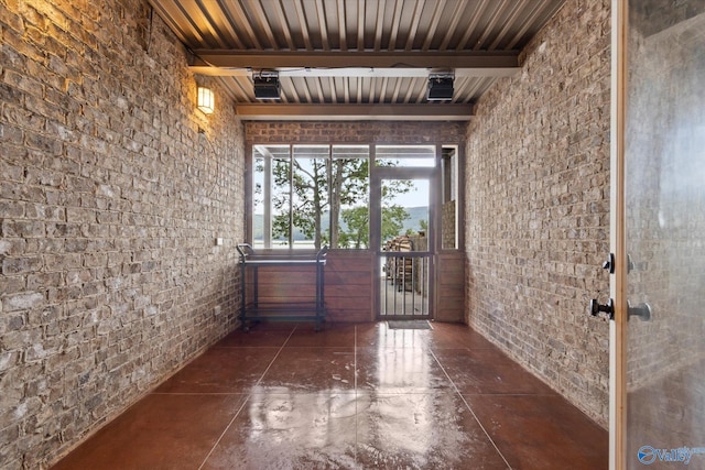 hall featuring brick wall and beam ceiling