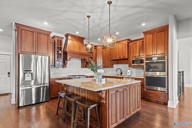 kitchen with premium range hood, a kitchen island, sink, hanging light fixtures, and stainless steel appliances