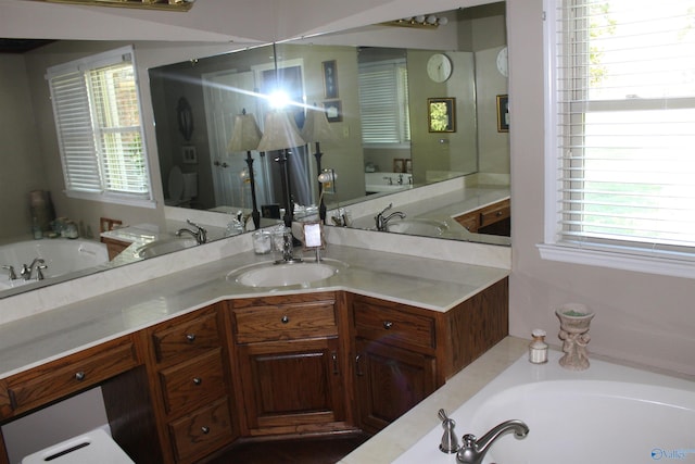 bathroom with a tub, a healthy amount of sunlight, and vanity