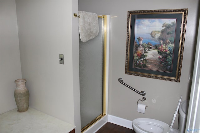 bathroom featuring a shower with door and toilet