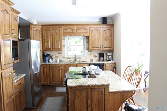 kitchen with decorative backsplash, stainless steel fridge with ice dispenser, a kitchen island, and sink