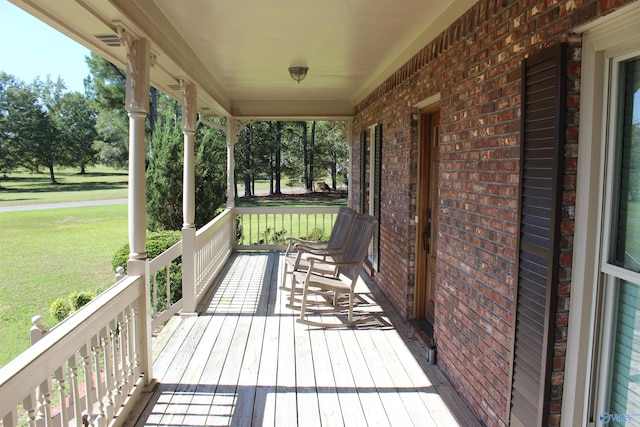 wooden deck featuring covered porch and a lawn