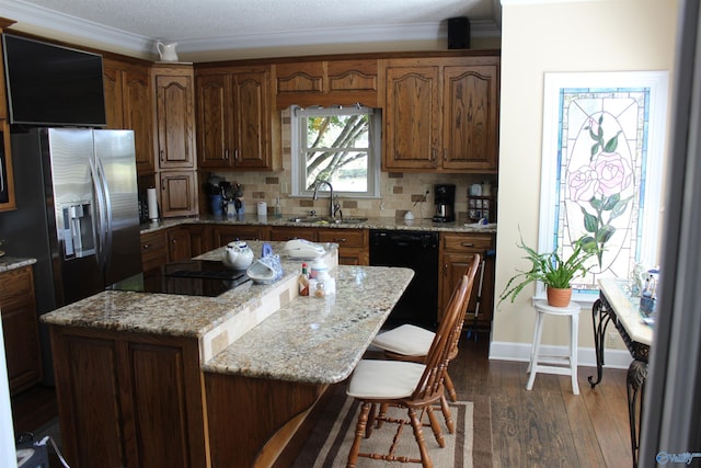 kitchen with tasteful backsplash, dark hardwood / wood-style flooring, sink, black appliances, and a kitchen bar