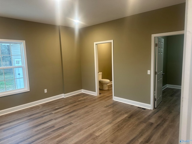 unfurnished bedroom with dark wood-type flooring and connected bathroom