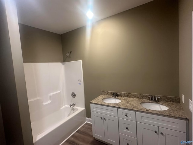 bathroom with bathing tub / shower combination, double vanity, and wood-type flooring