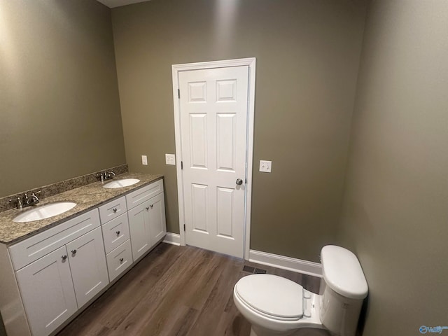 bathroom with double vanity, hardwood / wood-style flooring, and toilet