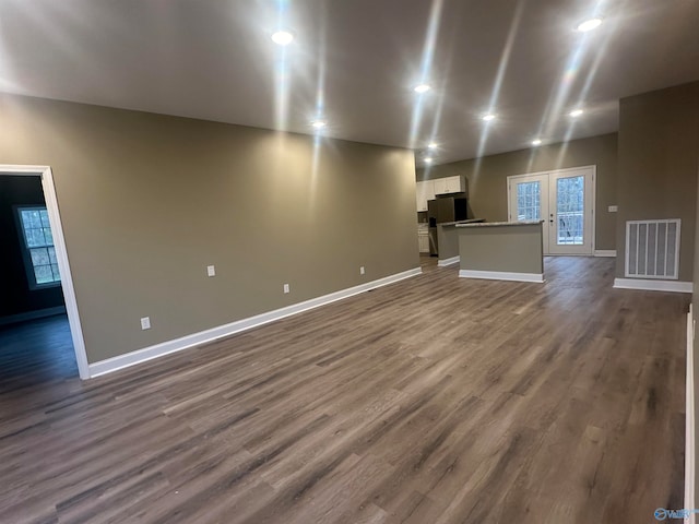 unfurnished living room with dark hardwood / wood-style flooring and french doors