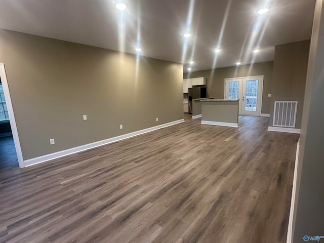 unfurnished living room featuring wood-type flooring and french doors