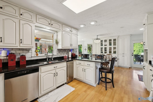 7734 Upper Snake Rd, Athens, AL 35614 - kitchen with a peninsula, dishwasher, a sink, light wood-style flooring, and backsplash