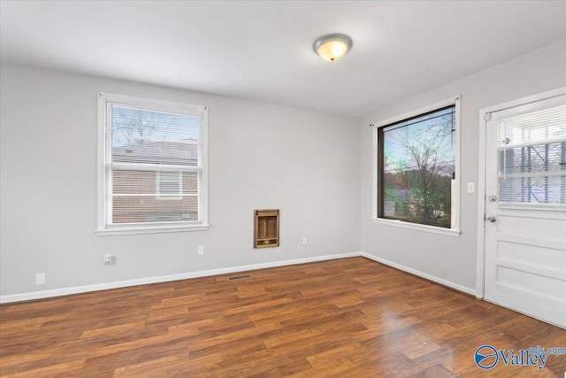 spare room with visible vents, baseboards, and wood finished floors