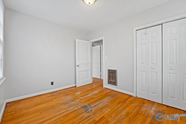 unfurnished bedroom with baseboards, a closet, visible vents, and light wood-style floors