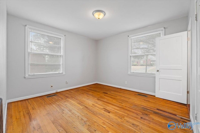 unfurnished room featuring light wood-style floors, visible vents, and baseboards