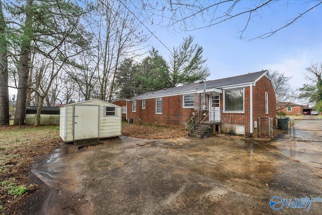 view of front of property featuring a shed, a gate, fence, and brick siding