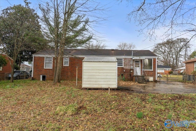 back of house featuring entry steps, brick siding, and fence