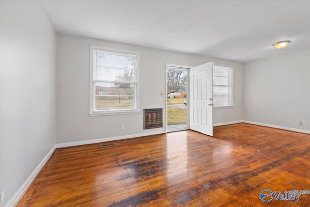 empty room featuring visible vents, baseboards, and wood finished floors