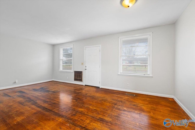 spare room featuring wood finished floors, visible vents, and baseboards