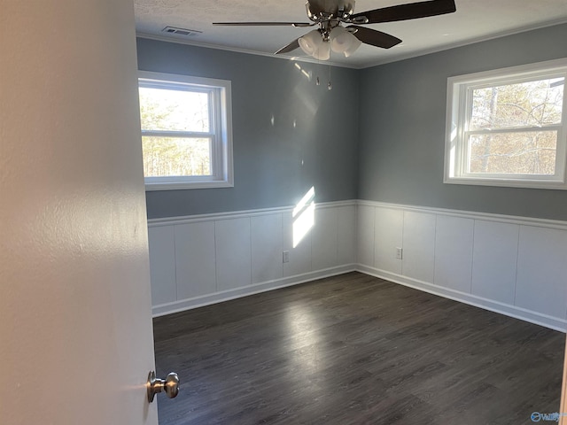 empty room with crown molding, dark wood-type flooring, and ceiling fan