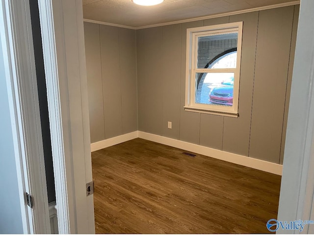 spare room featuring ornamental molding and dark wood-type flooring