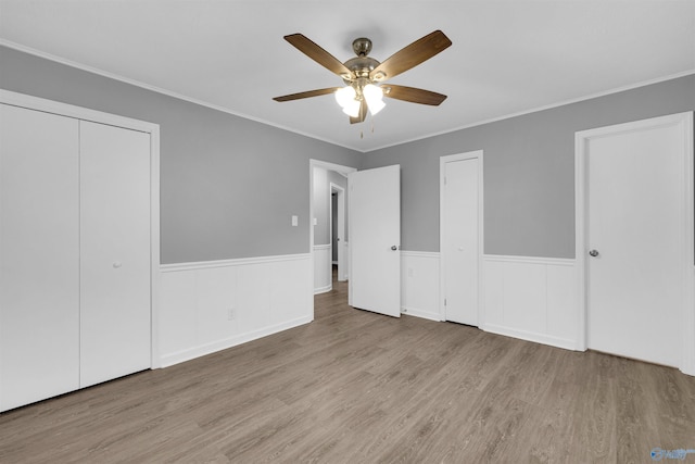 unfurnished bedroom with multiple closets, ornamental molding, ceiling fan, and light hardwood / wood-style flooring