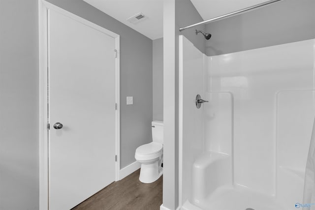 bathroom with toilet, hardwood / wood-style floors, and a shower