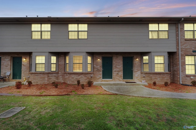 view of property featuring brick siding and a yard