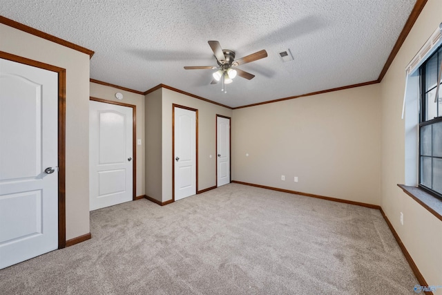 unfurnished bedroom featuring carpet flooring, ornamental molding, and visible vents