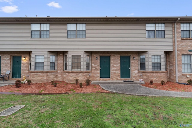 view of property featuring brick siding and a front yard